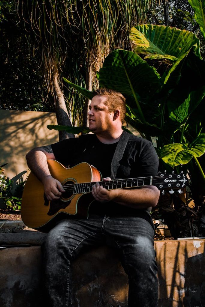 Young male guitarist performing in park