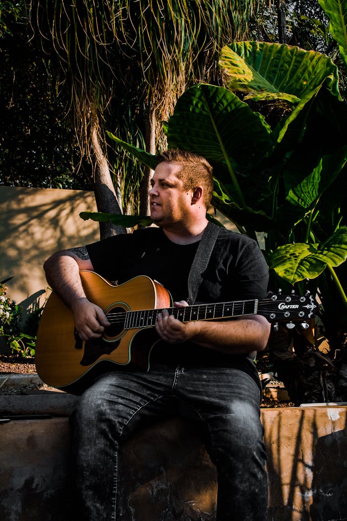 Young male guitarist performing in park